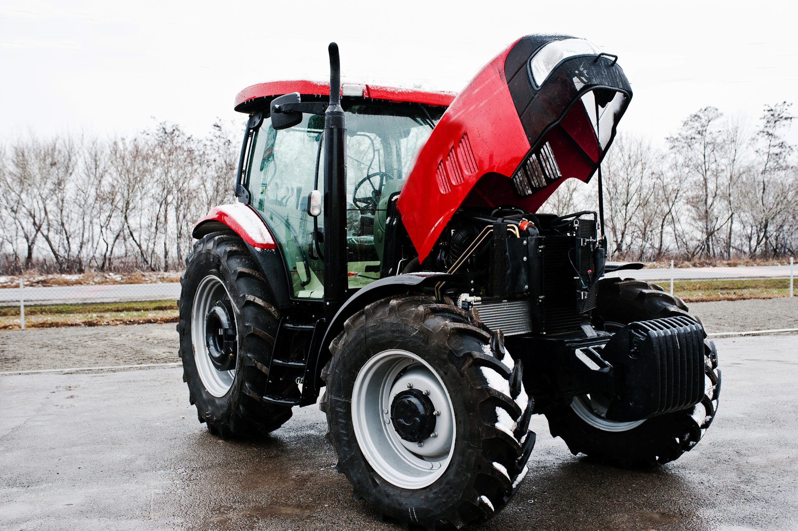 New red tractor with open motor at snowy weather